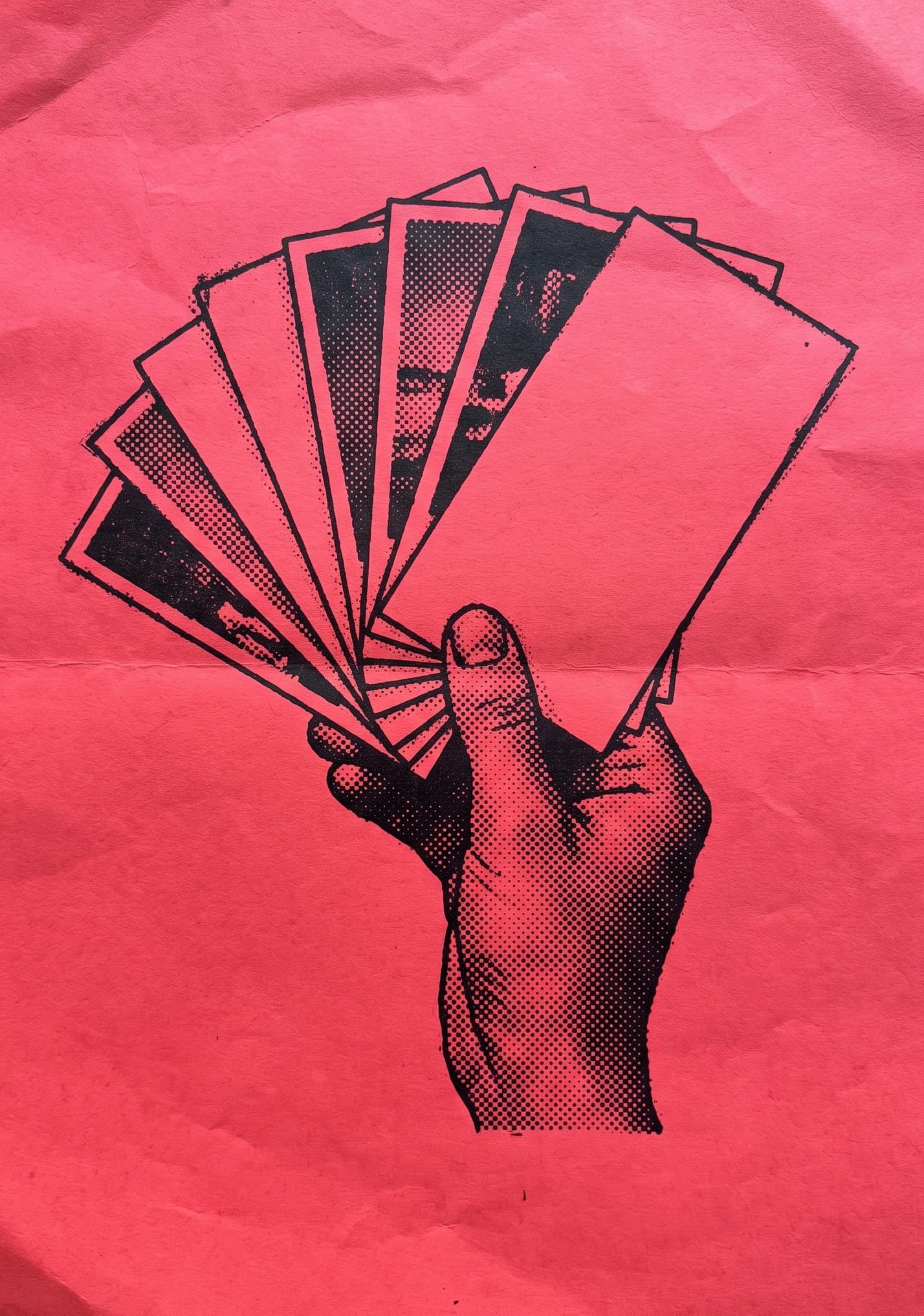 A hand fanning out a set of cards, on red paper